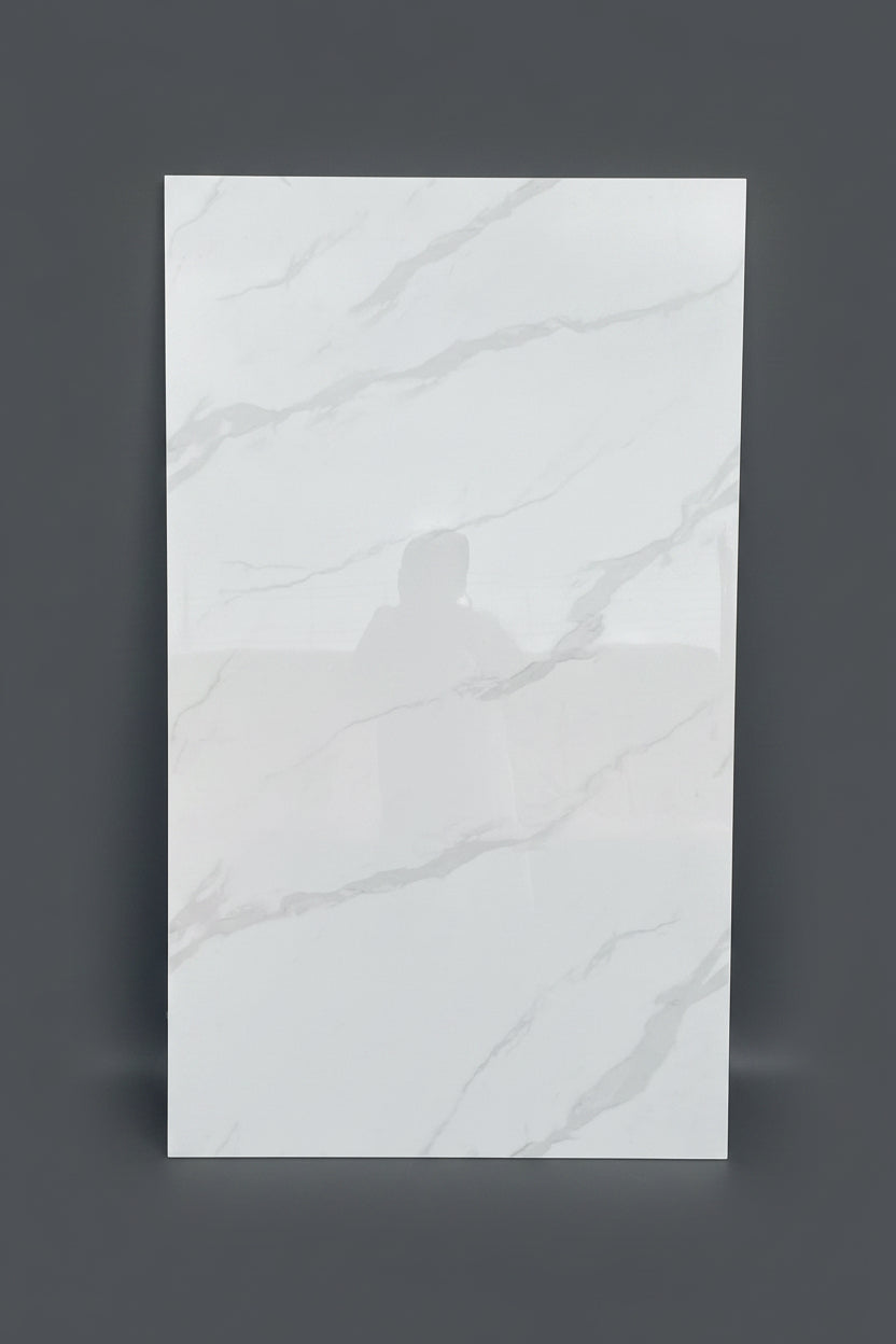 A large rectangular white porcelain tile with light gray marble-style veining, standing upright in a warehouse or showroom setting with cardboard boxes stacked in the background.