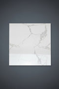A large square white marble-patterned floor tile is shown on a beige tiled floor, with a smaller matching tile.