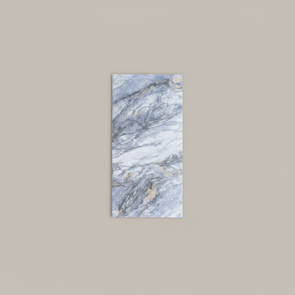 A rectangular marble-look tile with blue, gray, and white veining lies on a beige tiled floor next to a person's legs wearing blue jeans and tan sandals.